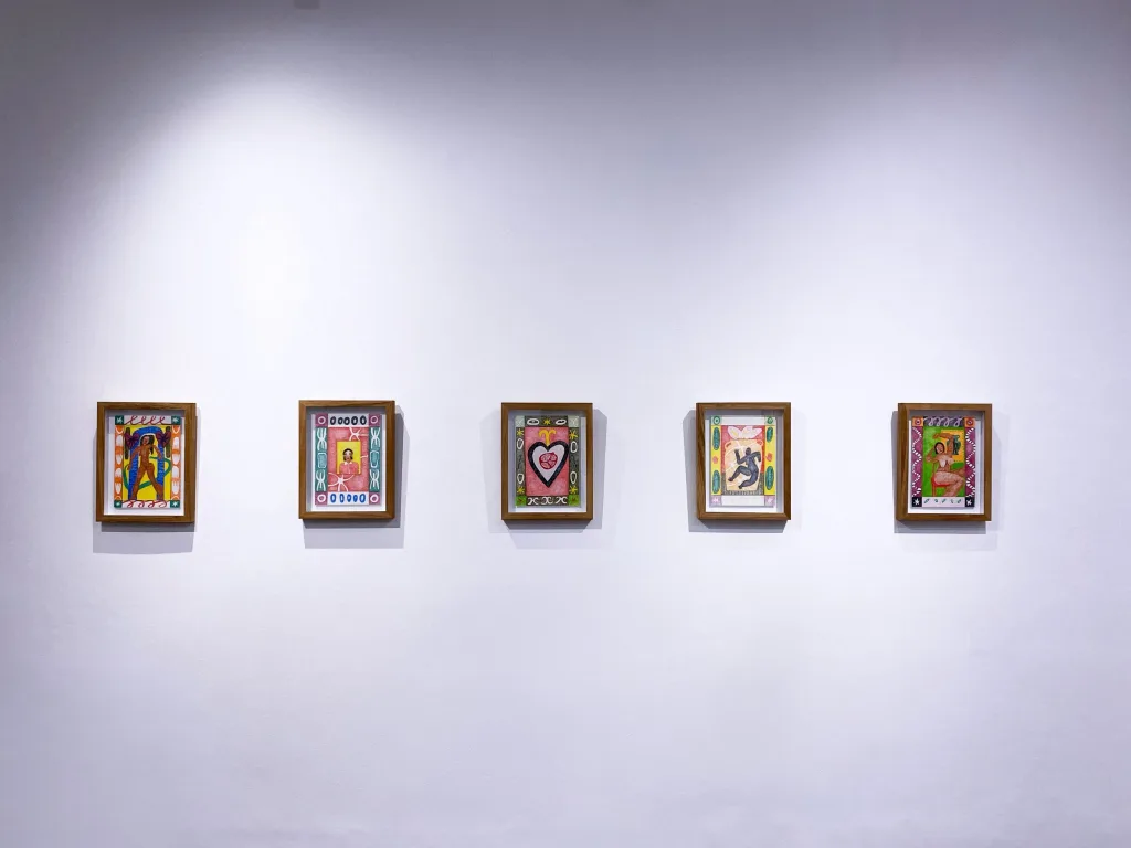 Five colorful framed artworks are evenly spaced on a white gallery wall, each featuring abstract patterns and bold designs.